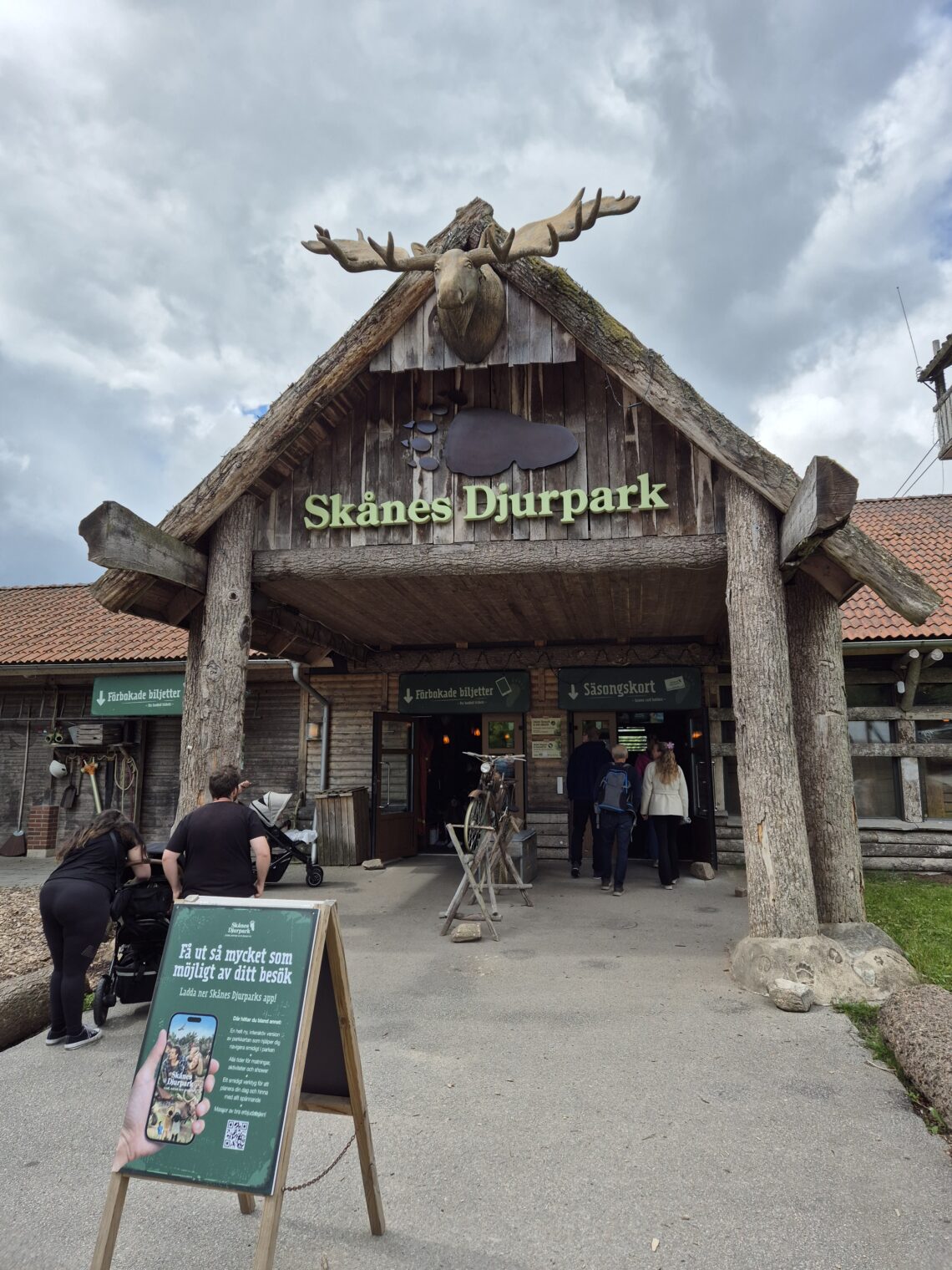 Entre till Skånes djurpark. Ett stort trähus med ett älghuvud på toppen.